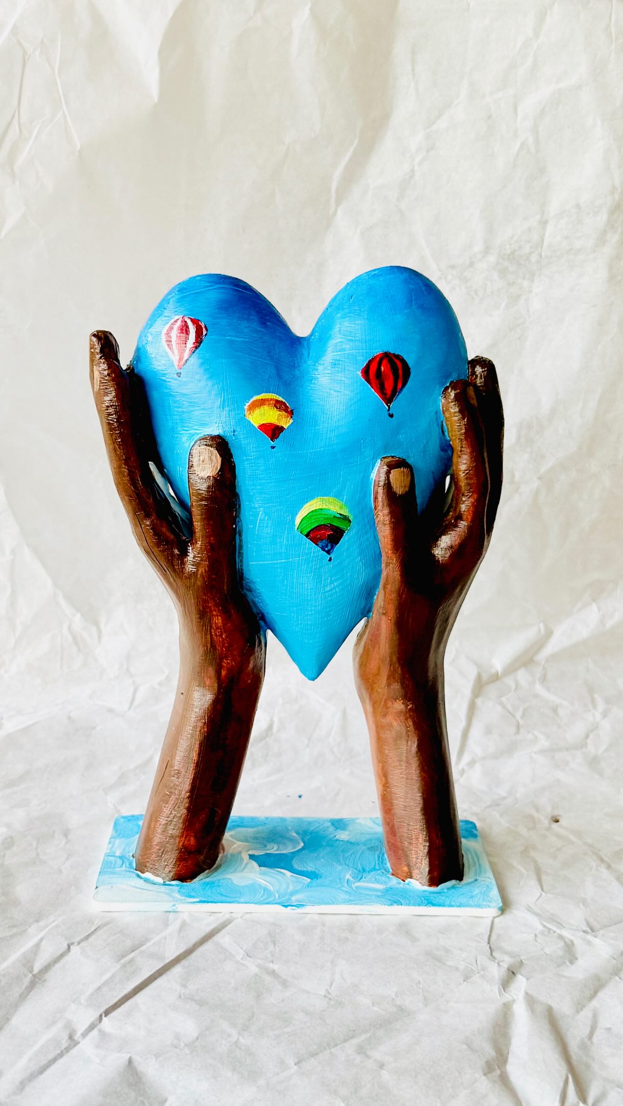 The Heart-Held Icon project is an initiative started by the MAD (Make A Difference) Leadership Foundation @madleadershipfoundation which was founded in 2003 by former Springbok captain Francois Pienaar after his promise to Nelson Mandela 23 years ago, to make a difference in South Africa. Together with a group of business leaders, he created MAD to support talented scholars from disadvantaged backgrounds, opening doors to quality schooling, mentorship, and opportunities that change lives.

Recently, MAD launched the Heart-Held Icon Project where well-known celebrities and artists have been invited to decorate a Heart-Held Sculpture, printed in plant-based bioplastic. This collection will be auctioned in London next week, with proceeds supporting MAD’s mission to open doors for even more young people with academic and leadership potential and inspiring the next generation of MAD leaders.

I am so honoured to be part of this campaign and am contributing three pieces to this year’s auction, each carrying a story close to my heart. This includes my own decorated Heart-Held Sculpture as well as a fine art print, and pack of postcards, of my portrait - The Age of Adolescence.

Together, these works celebrate the courage it takes to grow, to hope, and to become - which is exactly what MAD Leadership Foundation strives to achieve through its work with South African youth.

📷 “High Hopes” is a Heart-held Icon depicting African hands cradling a heart adorned with hot air balloons. I chose these motifs as a way of symbolising dreams and ambitions rising skyward. It speaks to the boundless hope that lives within every community, every young person, every act of reaching upward.
