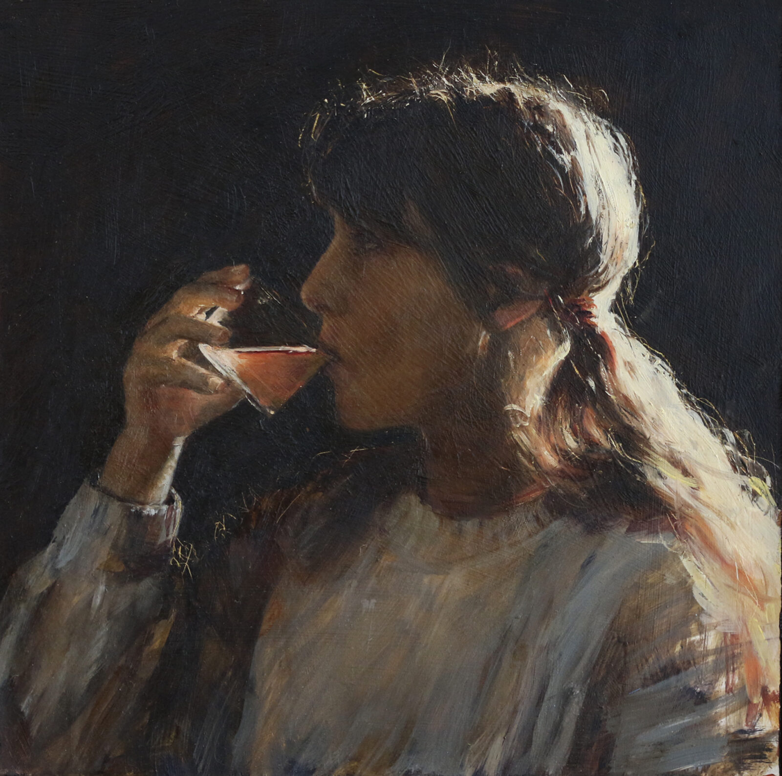 Portrait of a young girl drinking from a glass, wearing a grey sweater