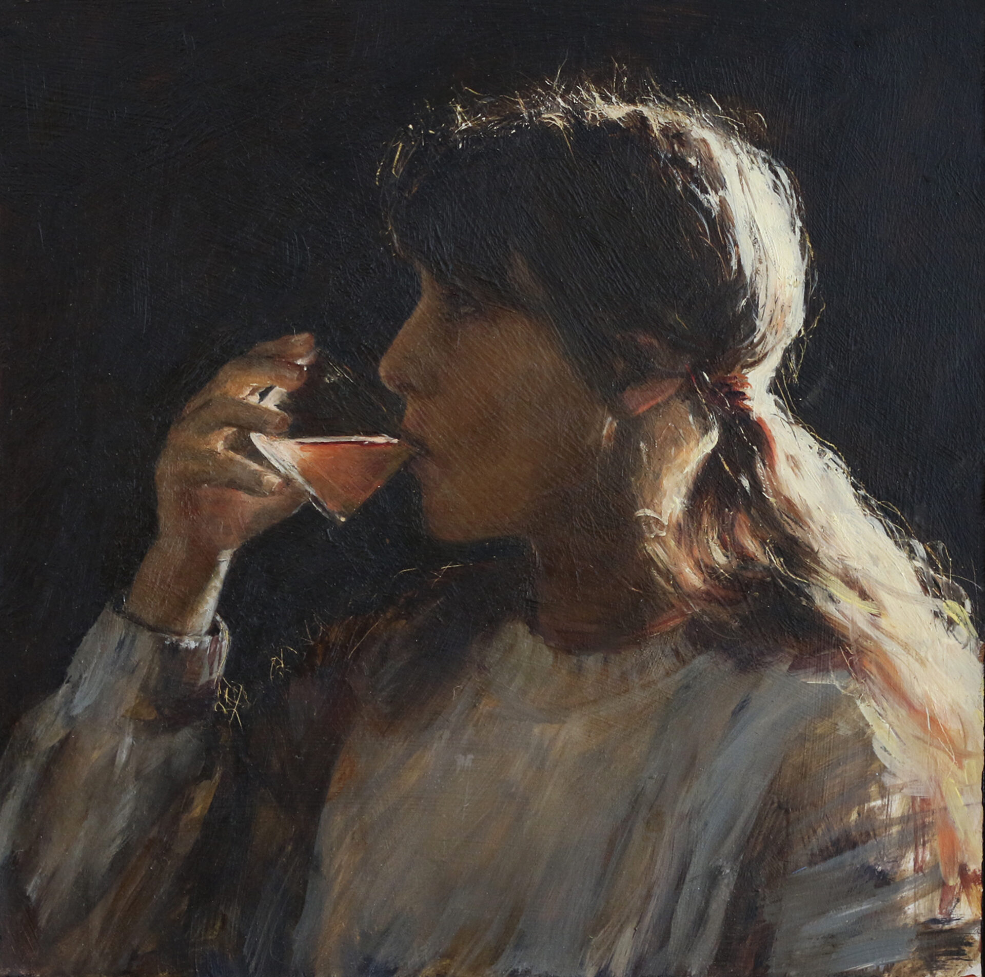 Portrait of a young girl drinking from a glass, wearing a grey sweater